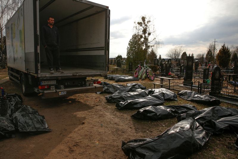 Funeral employee looks at civilian corpses as Russia's offensive on Ukraine continues