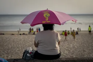 A woman protects herself from the sun under her umbrella on a beach in Cadiz, Spain, on Monday, June 13, 2022.