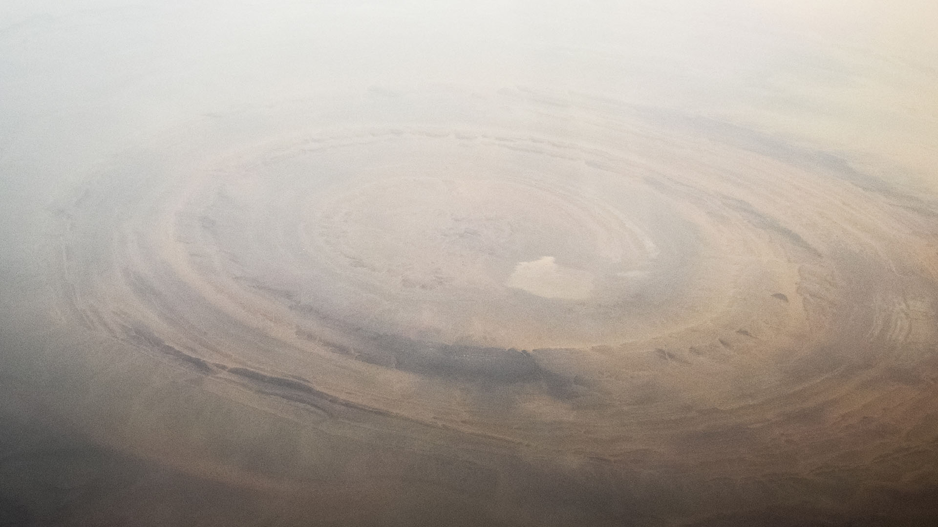 Sahara Desert, Mauritania: Aerial view of the Richât structure, also known as Guelb er Richât, "Eye of Africa" or "Eye of the desert" It is a severely eroded elliptical geological dome 40 kilometers (25 miles) in diameter in the Adrar Plateau in the Sahara, near Oueddan, west-central Mauritania.